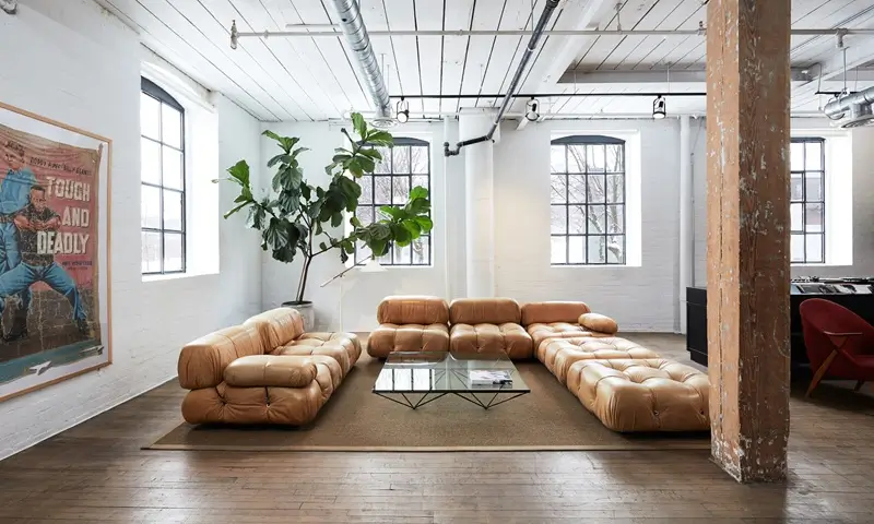 Global Collective Toronto | East Room Premium Coworking Virtual office rental Toronto Canada - East Room industrial character loft with leather sofa, vintage decor, large windows and white brick